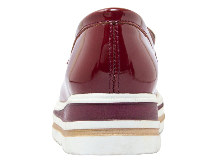 Zapato tipo mocasín para niño en charol color vino con suela blanca de plataforma gruesa.