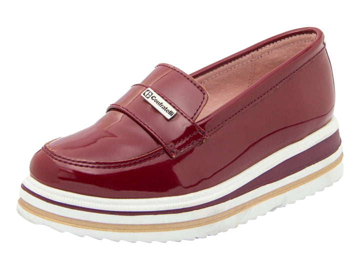 Zapato tipo mocasín para niño en charol color vino con suela blanca de plataforma gruesa.