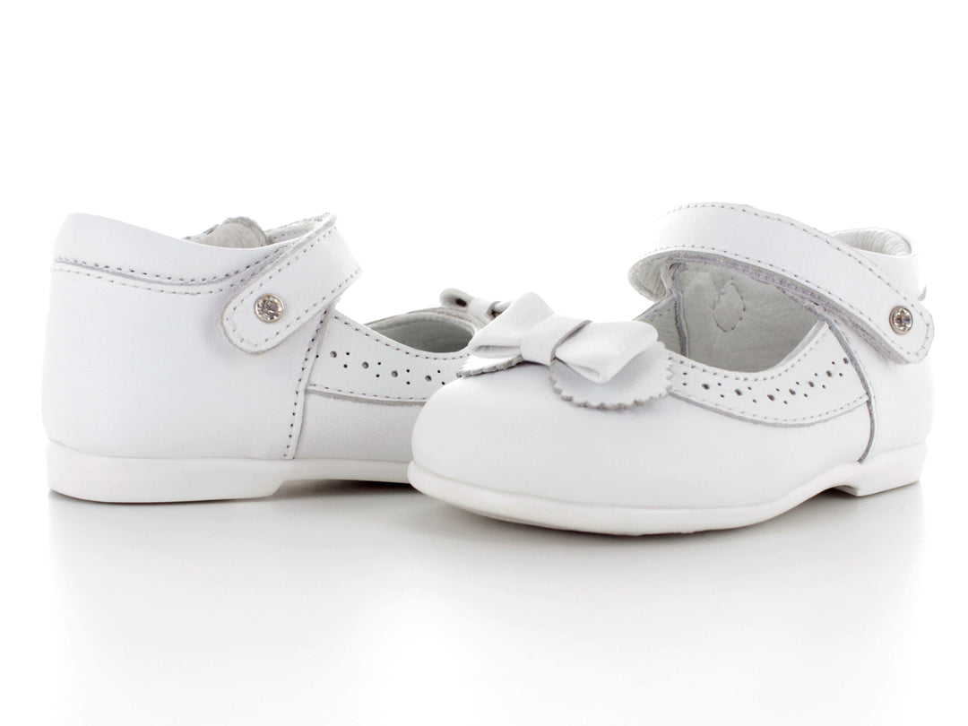 Par de zapatos blancos para bebé con moño decorativo y correa ajustable.