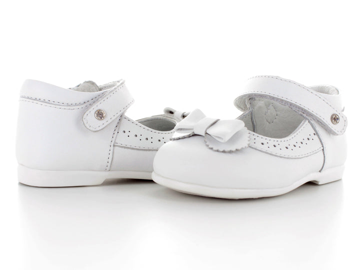 Par de zapatos blancos para bebé con moño decorativo y correa ajustable.
