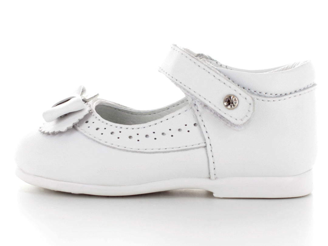 Par de zapatos blancos para bebé con moño decorativo y correa ajustable.