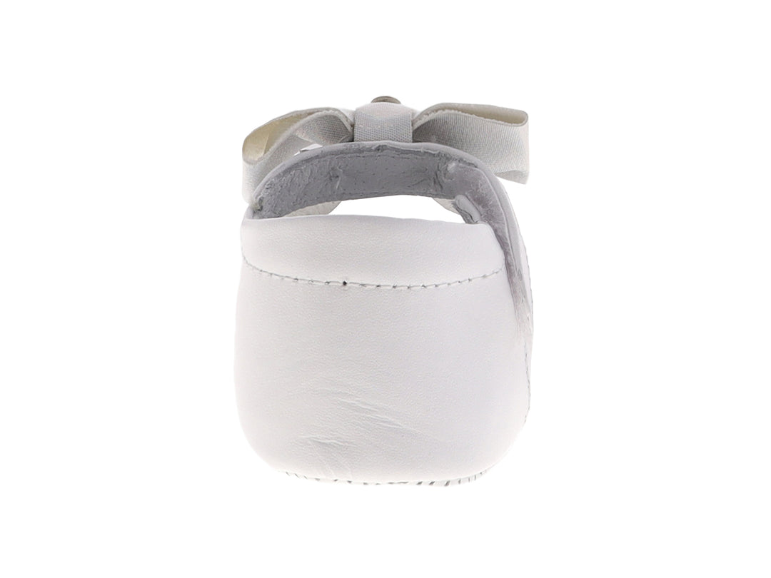 Zapato blanco para bebé estilo Mary Jane con moño decorativo y detalles perforados.