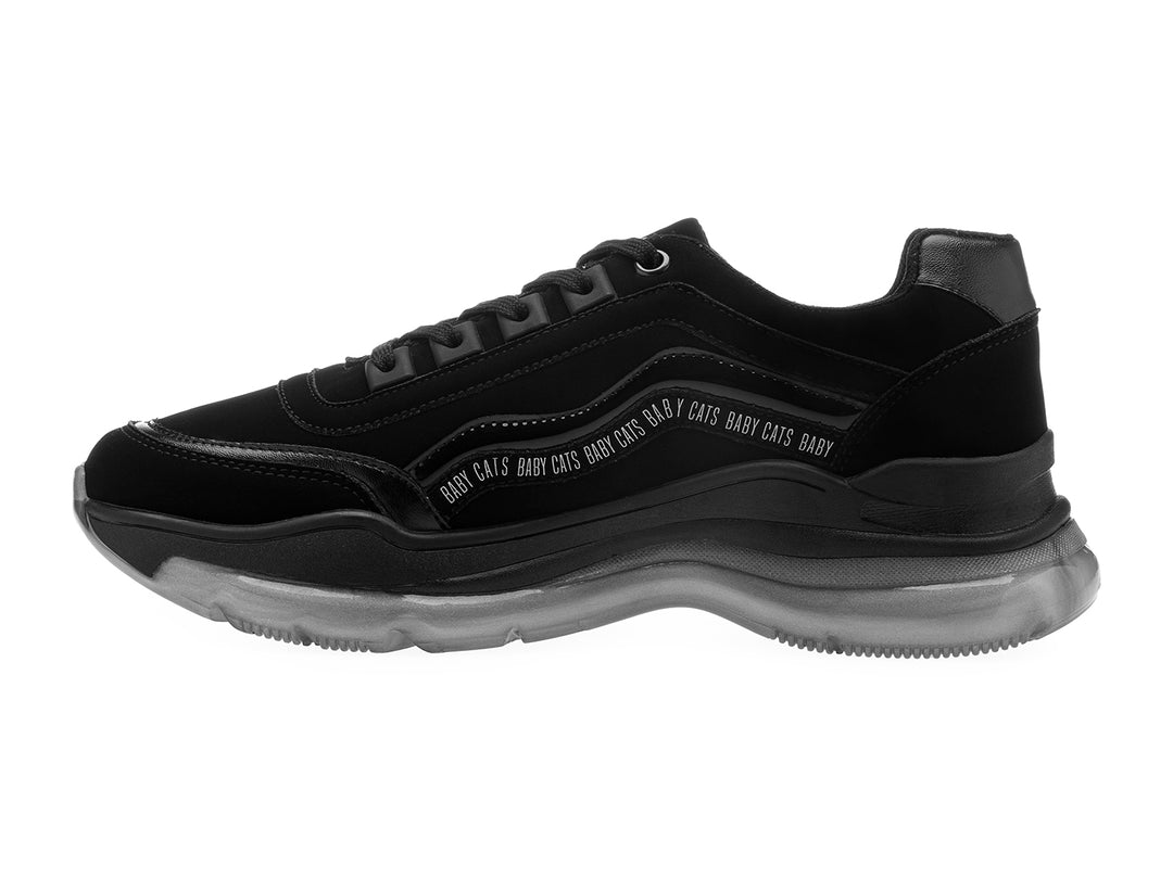 Tenis negros de estilo deportivo con suela gruesa gris translúcida y detalles de texto blanco en el lateral
