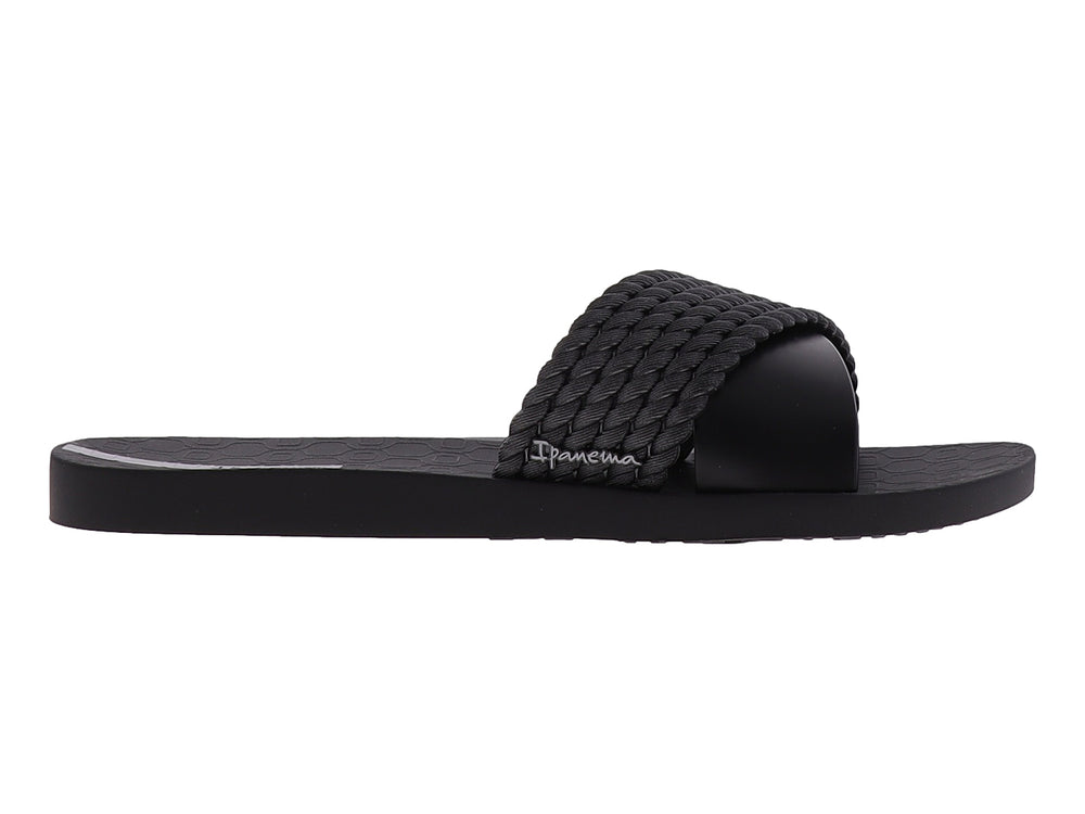 Sandalia Ipanema de color negro con correa superior trenzada y suela plana.