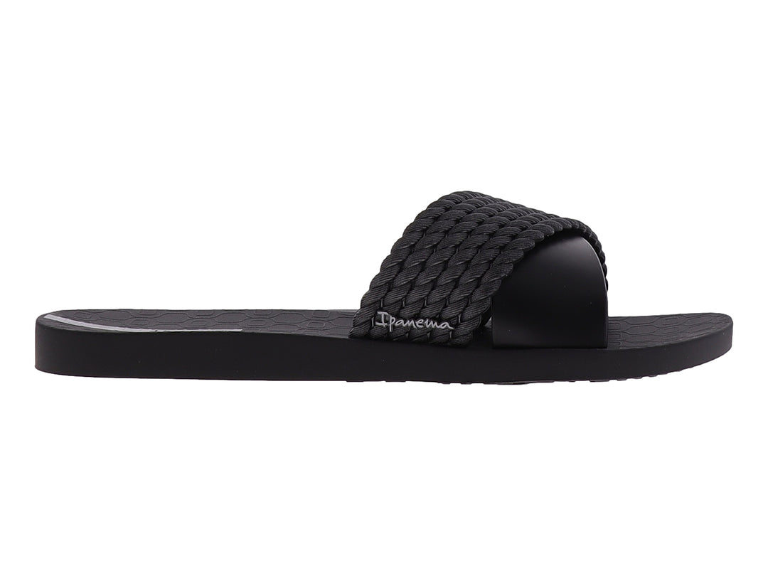 Sandalia Ipanema de color negro con correa superior trenzada y suela plana.