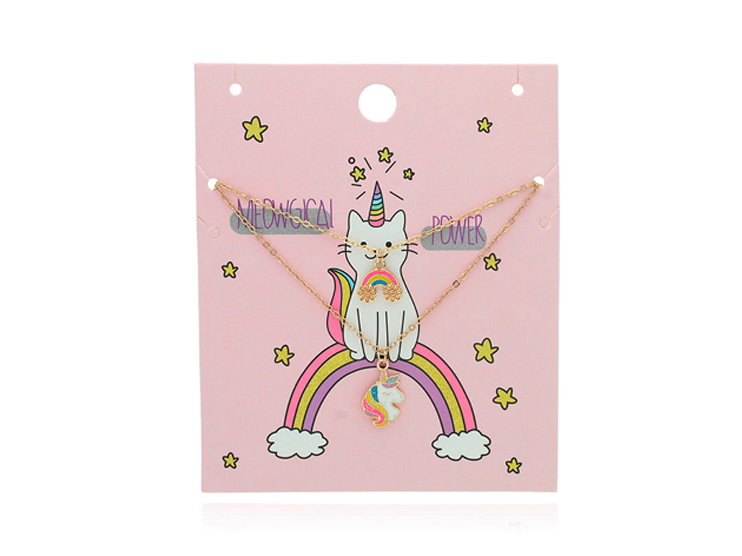 Conjunto de dos collares dorados con dijes de arcoíris y unicornio sobre fondo rosa.