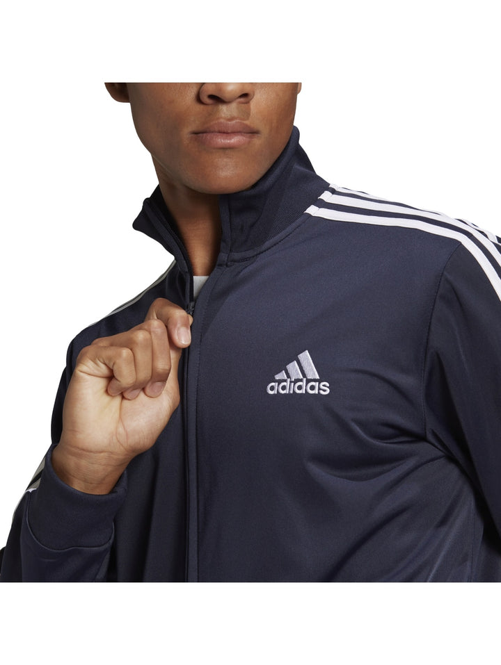 Hombre vistiendo conjunto deportivo Adidas azul marino con tres franjas blancas laterales.