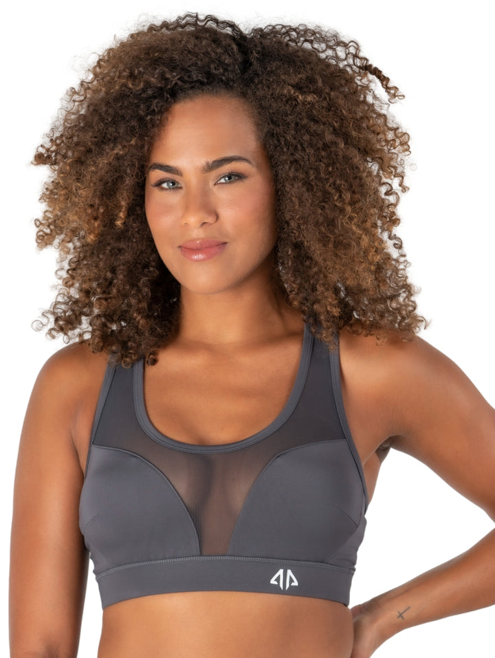 Mujer vistiendo un bra deportivo Alpha Prime color gris humo con panel frontal de malla transparente.
