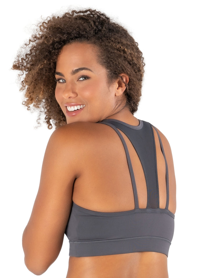 Mujer vistiendo un bra deportivo Alpha Prime color gris humo con panel frontal de malla transparente.