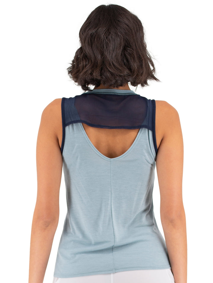 Mujer vistiendo una camiseta deportiva sin mangas de color azul claro con bordes en azul oscuro.