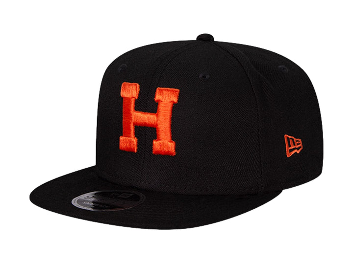 Gorra de béisbol New Era color negro con letra H bordada en naranja y visera plana.