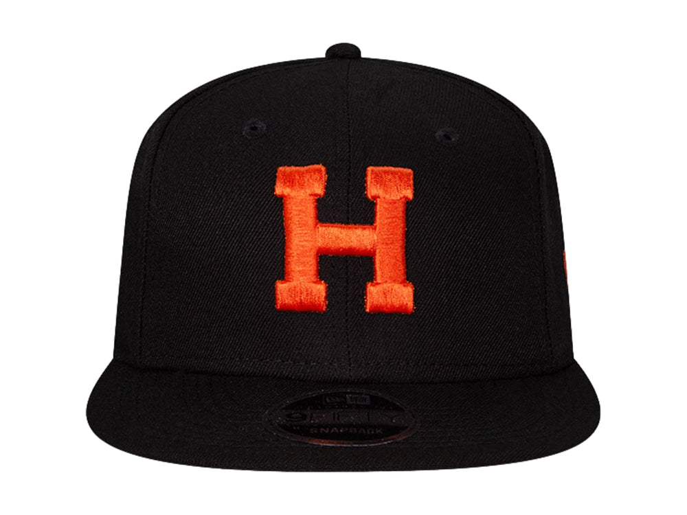 Gorra de béisbol New Era color negro con letra H bordada en naranja y visera plana.