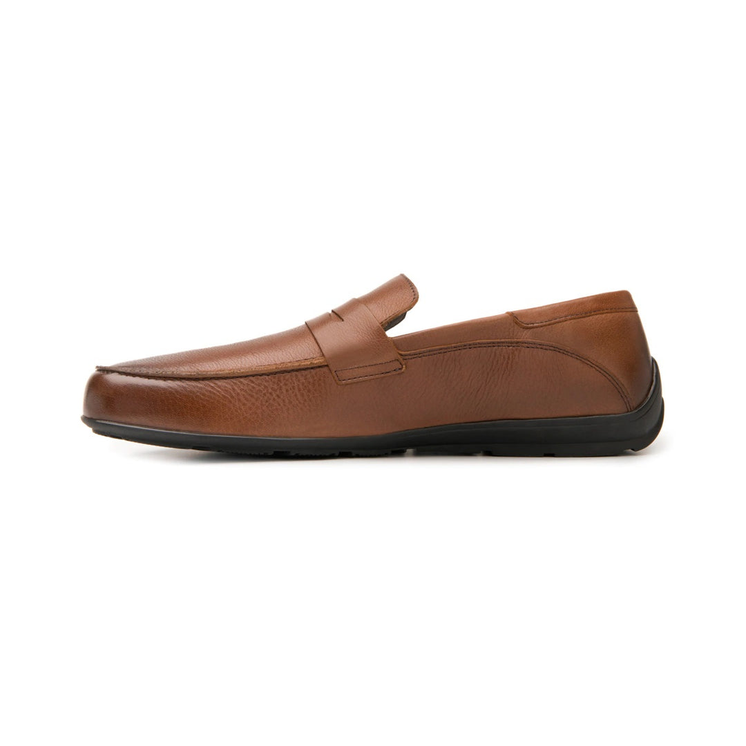 Zapato tipo mocasín color café con suela negra.