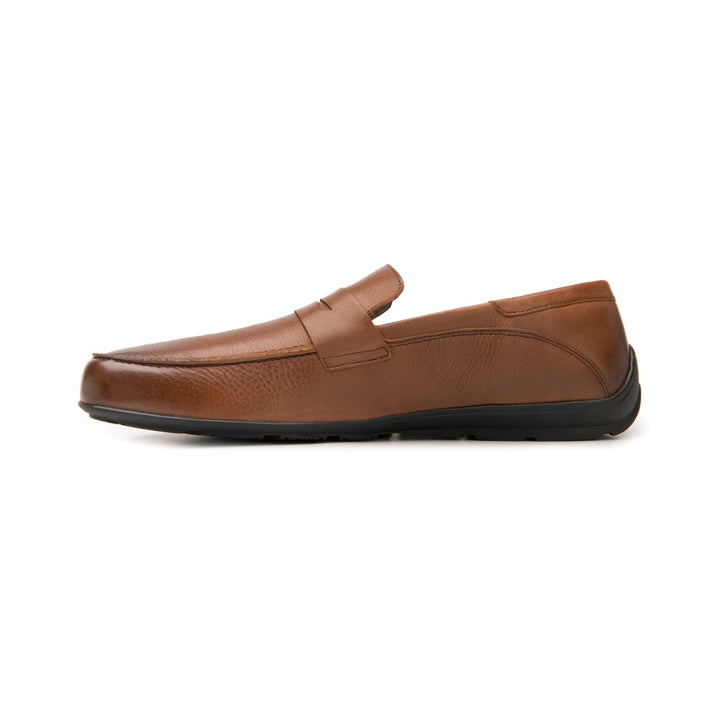 Zapato tipo mocasín color café con suela negra.