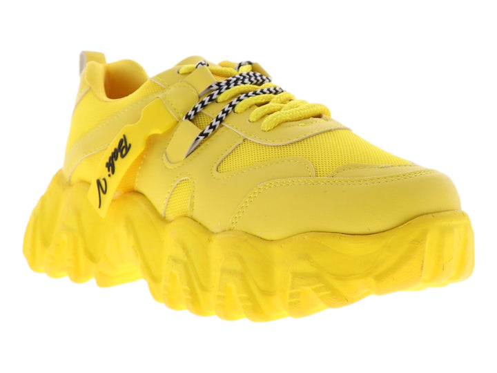 Tenis deportivos color amarillo con suela chunky y agujetas con detalles en blanco y negro.