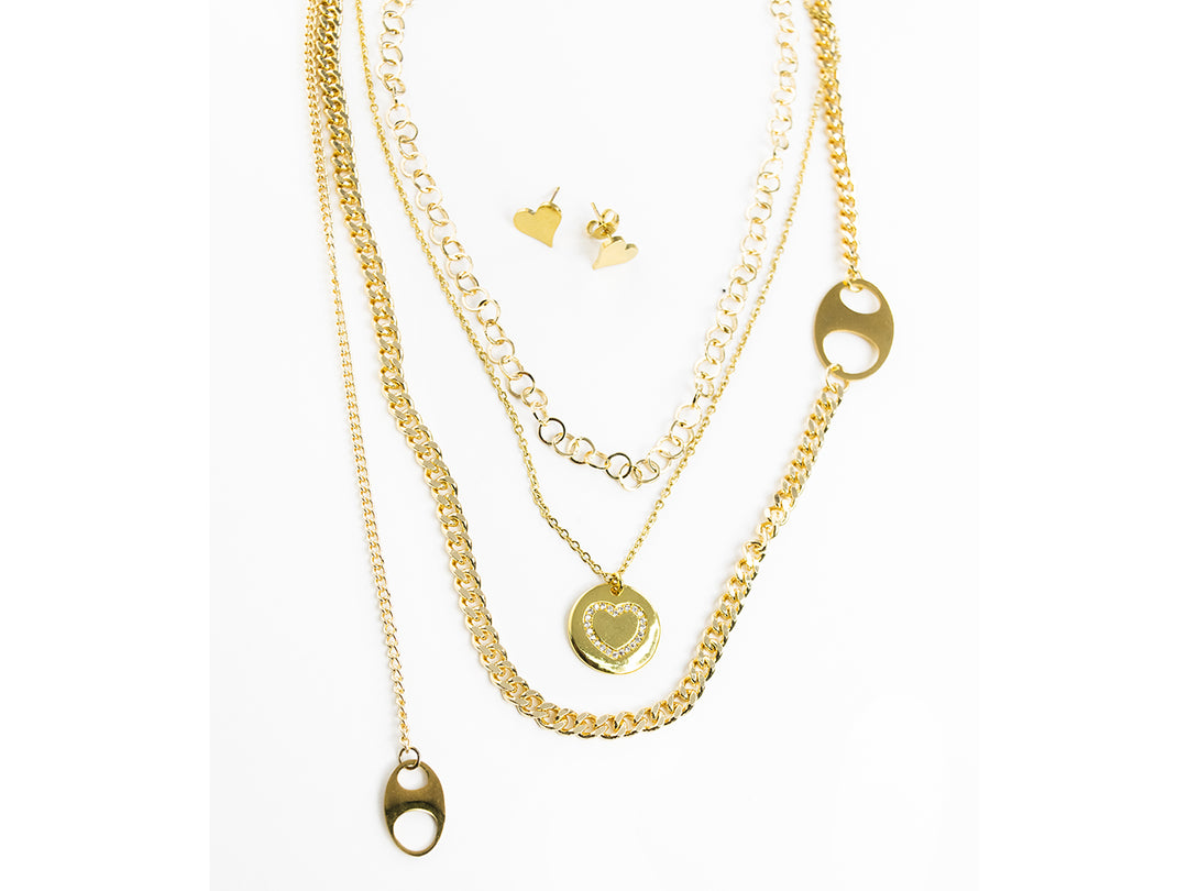Set de collares en capas con dije de corazón y aretes a juego en color dorado sobre fondo blanco.
