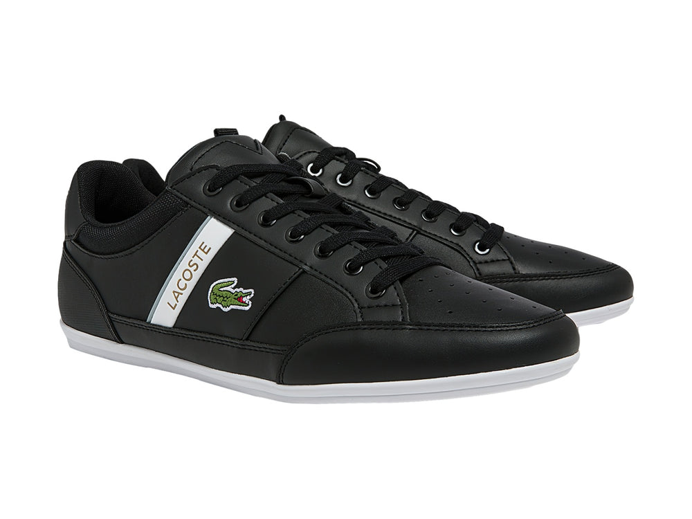Tenis Lacoste color negro con franja blanca lateral y suela blanca.