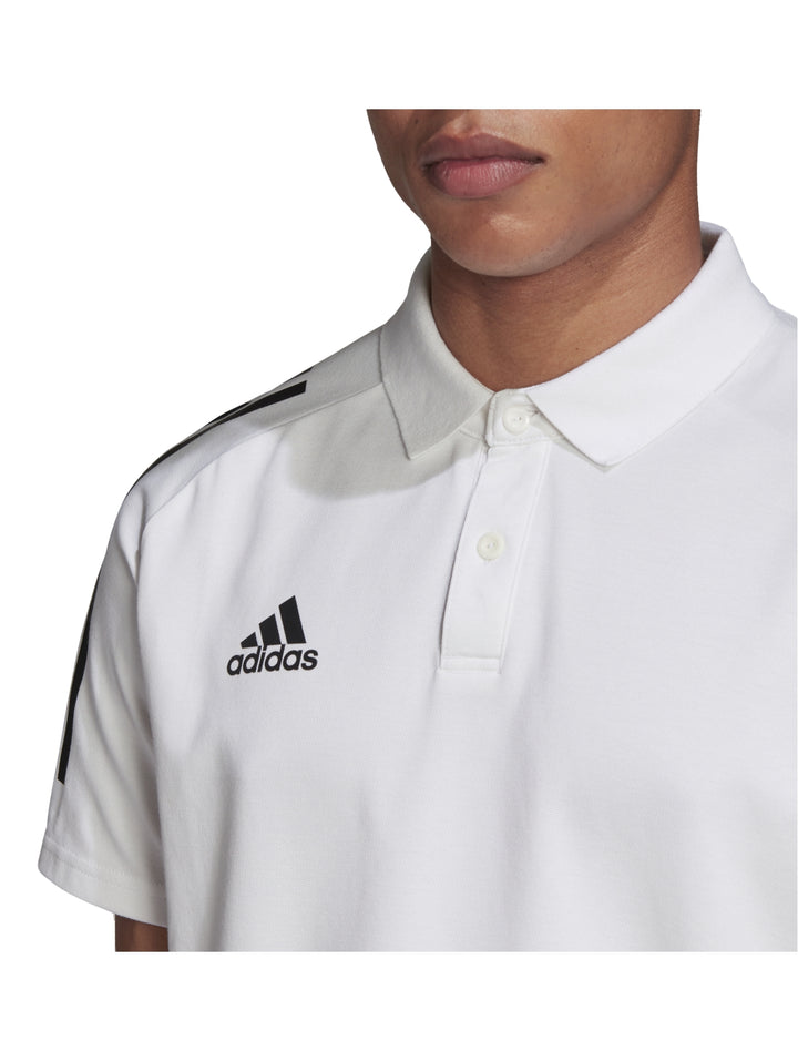 Hombre vistiendo playera polo blanca de Adidas con rayas negras en los hombros.