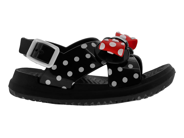 Sandalia negra brillante para niña con moño rojo y blanco con lunares y tiras decoradas con puntos blancos.