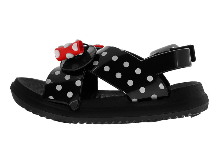 Sandalia negra brillante para niña con moño rojo y blanco con lunares y tiras decoradas con puntos blancos.