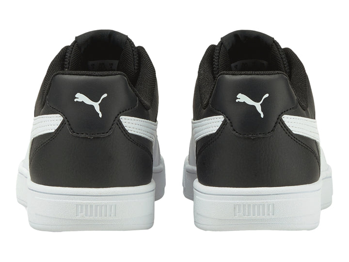 Tenis PUMA Caven JR en color negro con franja lateral y suela en color blanco para niño.