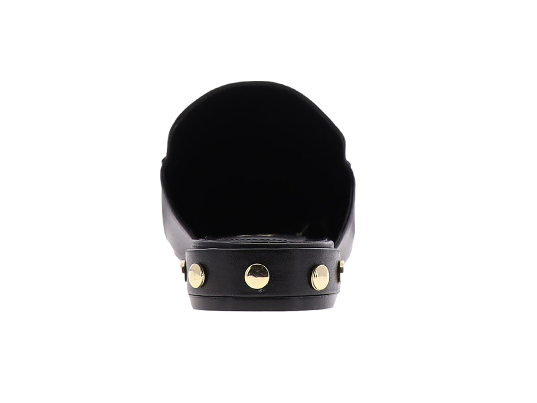 Zapato mule de cuero negro con herraje metálico dorado en la parte superior.