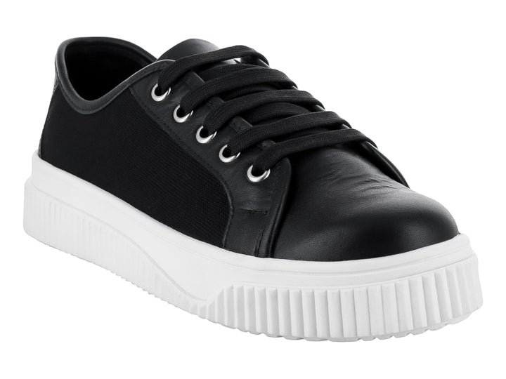 Tenis negros con suela blanca gruesa y cordones negros.