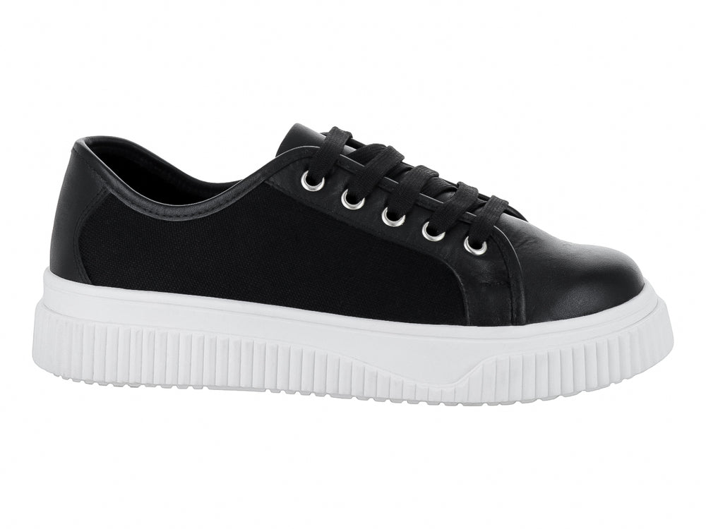 Tenis negros con suela blanca gruesa y cordones negros.