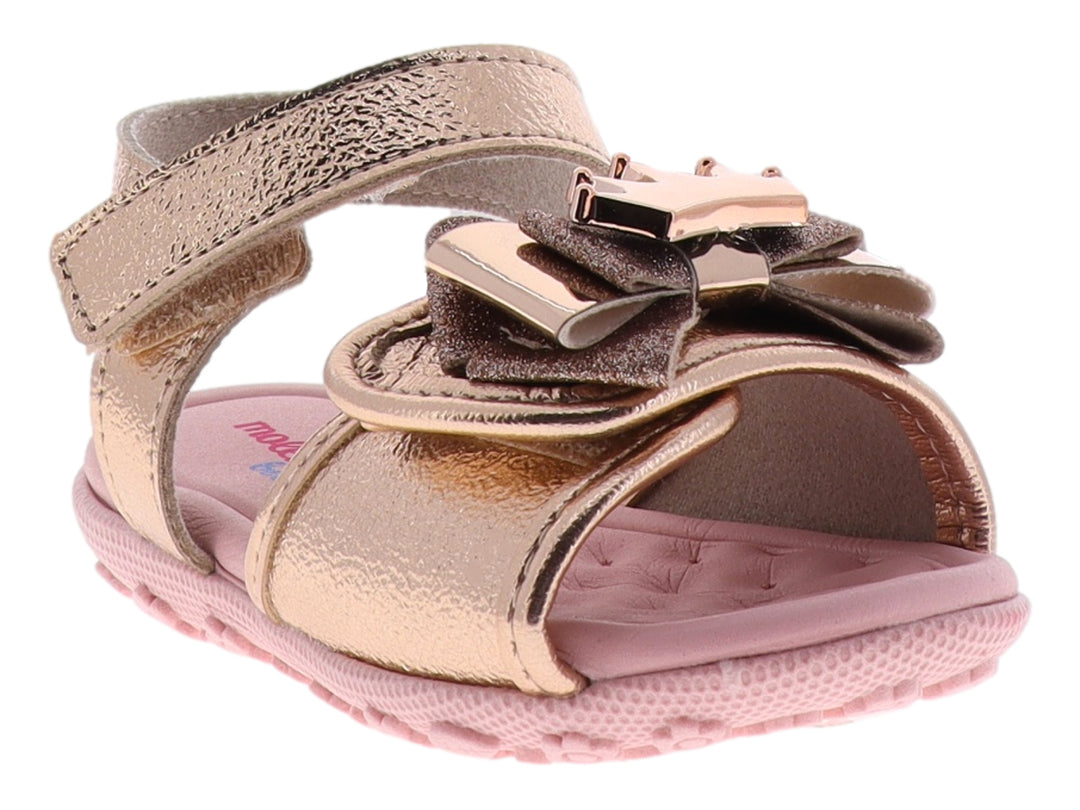 Sandalia para niña color oro rosado metalizado con adorno de moño y suela rosa.