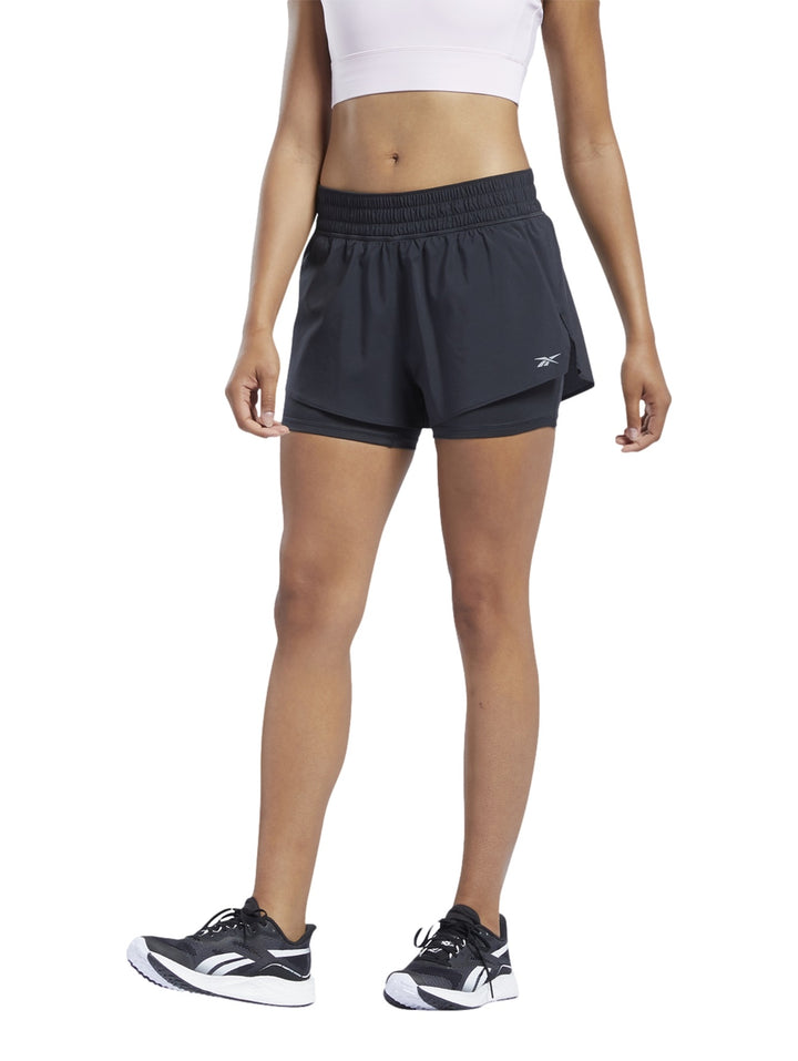 Mujer usando shorts deportivos Reebok color negro modelo 2 en 1.