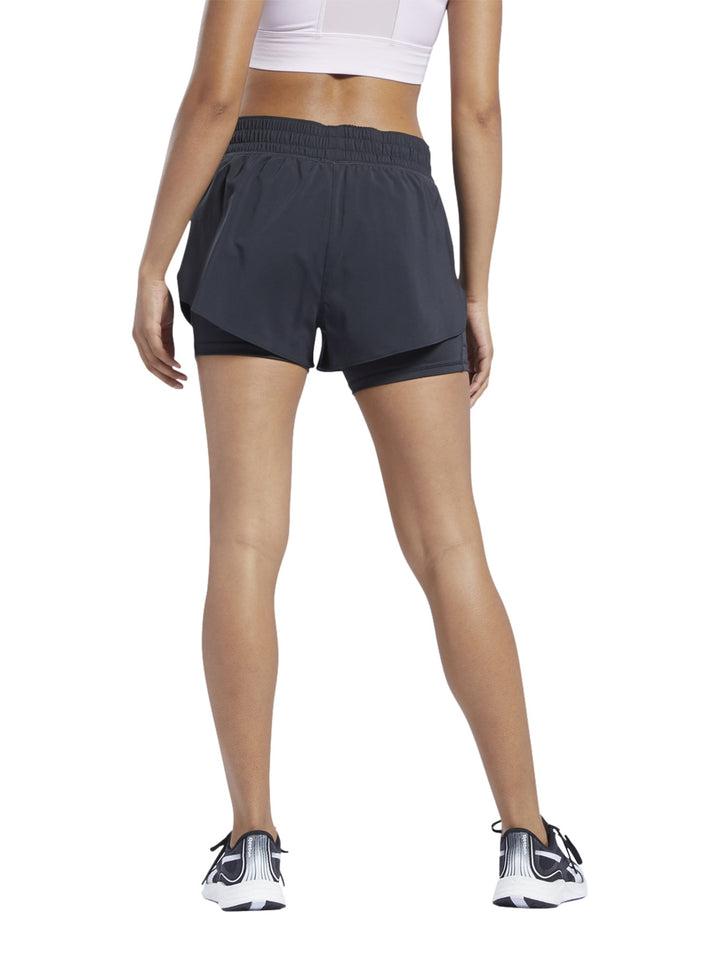 Mujer usando shorts deportivos Reebok color negro modelo 2 en 1.