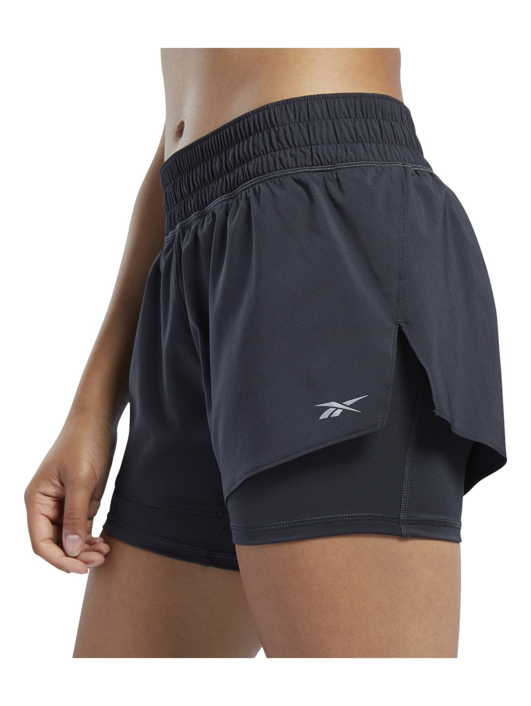 Mujer usando shorts deportivos Reebok color negro modelo 2 en 1.