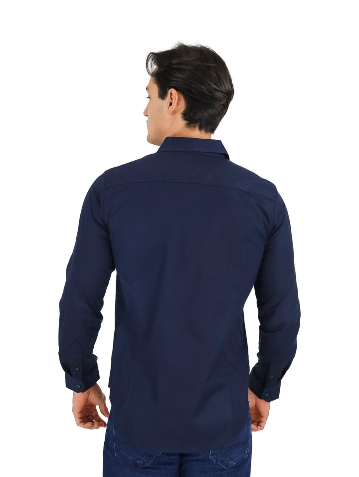 Hombre vistiendo una camisa de manga larga color azul marino y pantalones vaqueros.