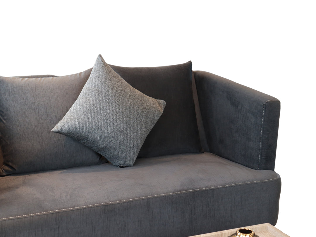 Conjunto de sala compuesto por dos sofás color gris con cojines y una mesa de centro rectangular.