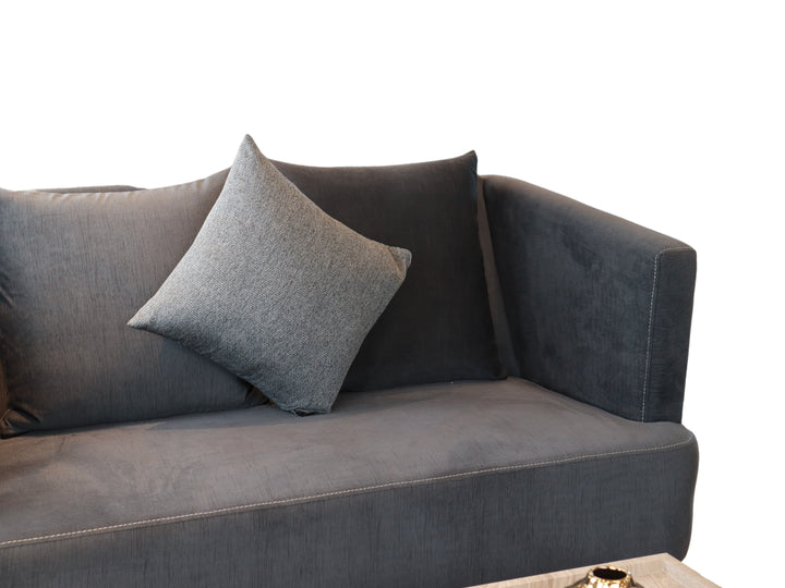 Conjunto de sala compuesto por dos sofás color gris con cojines y una mesa de centro rectangular.