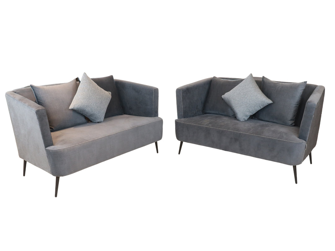 Conjunto de sala compuesto por dos sofás color gris con cojines y una mesa de centro rectangular.