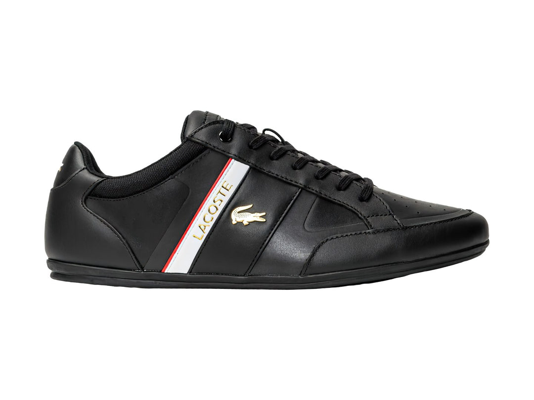 Tenis Lacoste color negro con franja blanca y roja lateral y logotipo del cocodrilo.