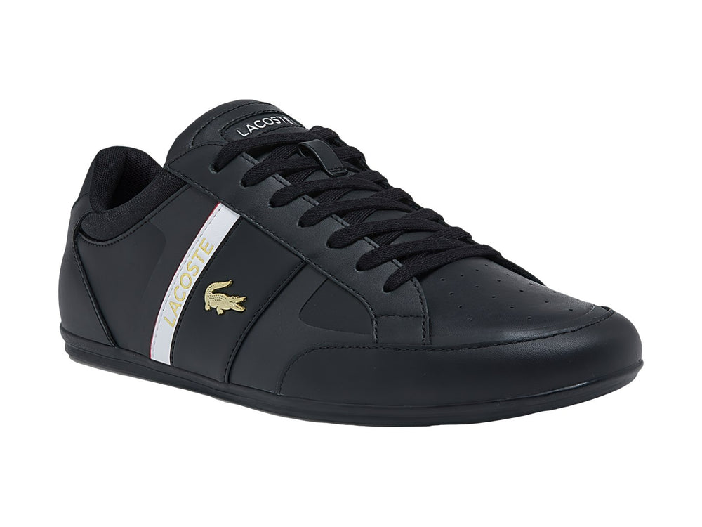Tenis Lacoste color negro con franja blanca y roja lateral y logotipo del cocodrilo.