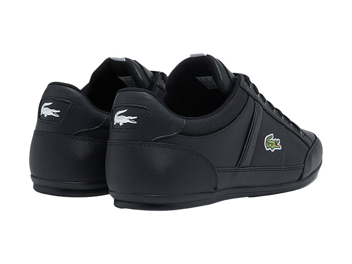 Tenis deportivos Lacoste color negro con cordones, vista lateral sobre fondo blanco.