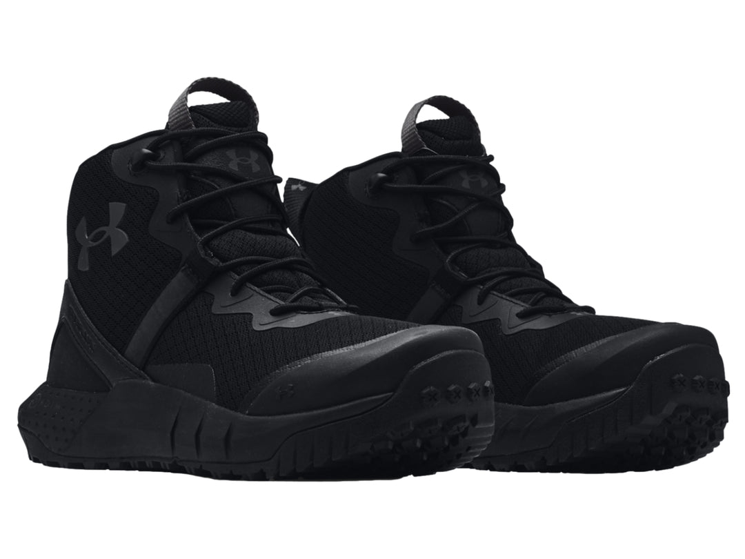 Bota deportiva Under Armour de color negro, corte medio con suela robusta y textura de malla.