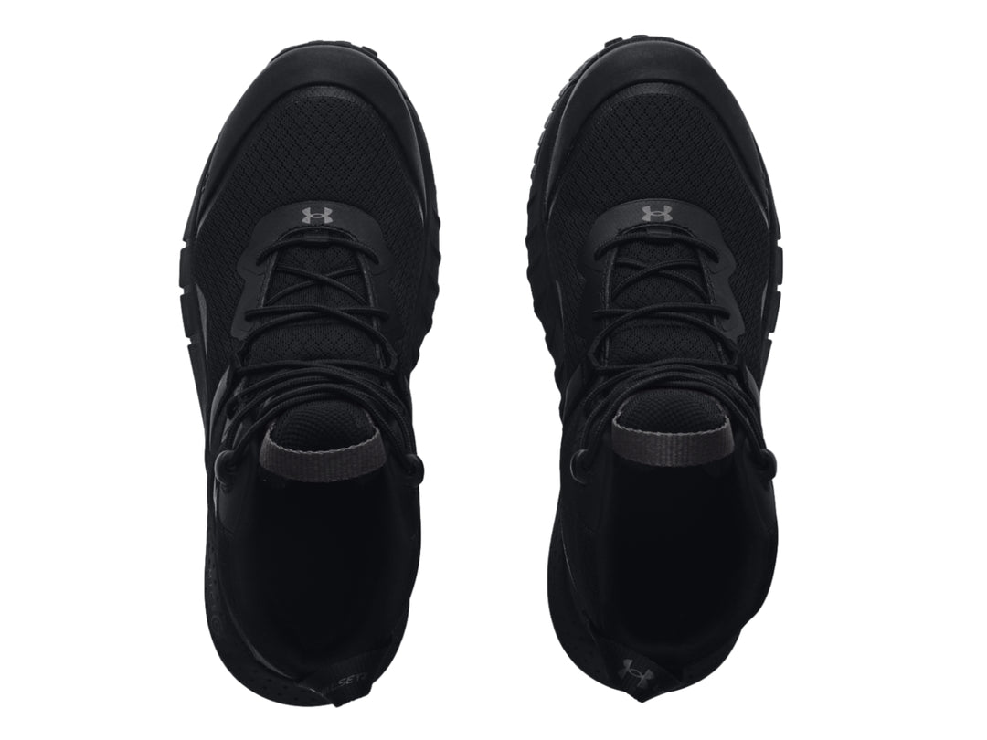 Bota deportiva Under Armour de color negro, corte medio con suela robusta y textura de malla.