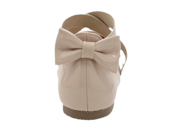 Zapato plano para niña en color rosa charol con tiras cruzadas y detalle de moño posterior.