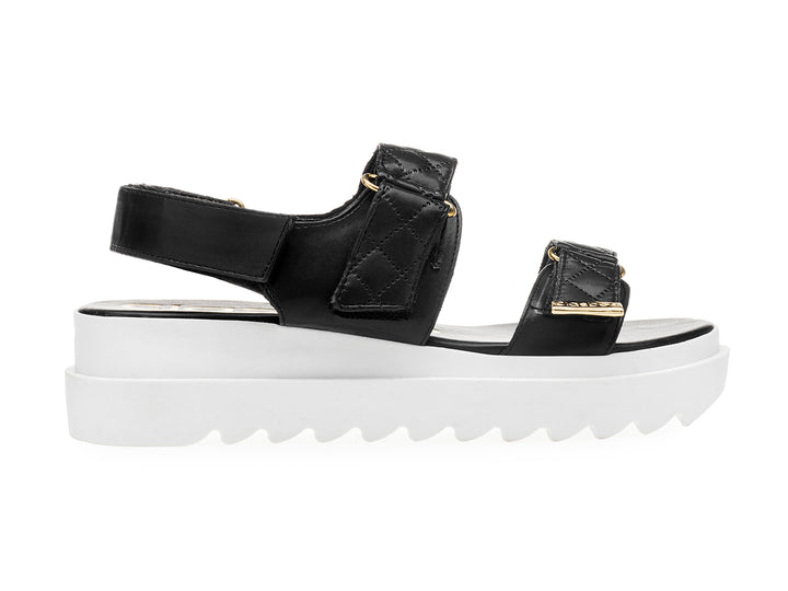 Sandalia negra de plataforma blanca con correas acolchadas y hebillas doradas para mujer.