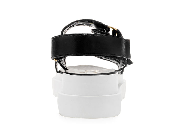 Sandalia negra de plataforma blanca con correas acolchadas y hebillas doradas para mujer.