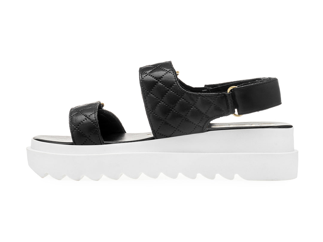 Sandalia negra de plataforma blanca con correas acolchadas y hebillas doradas para mujer.