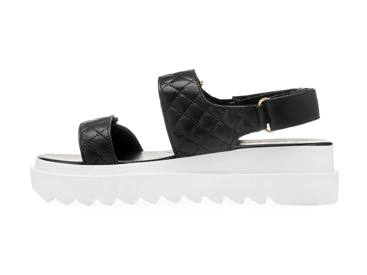 Sandalia negra de plataforma blanca con correas acolchadas y hebillas doradas para mujer.