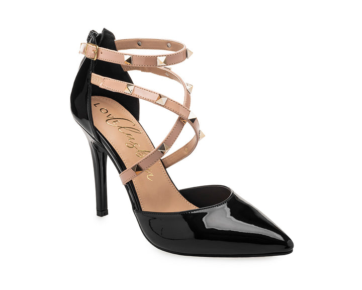 Zapato de tacón alto negro brillante con tiras beige decoradas con estoperoles dorados y punta fina.