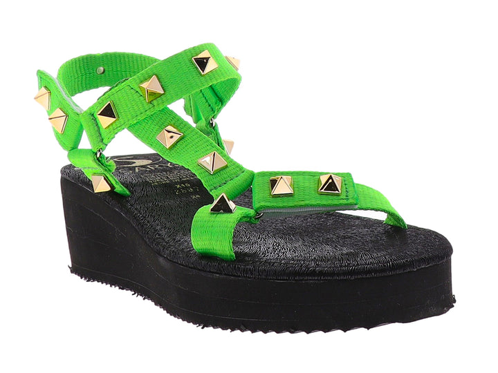 Sandalia de plataforma negra con tiras verde neón y tachuelas doradas.