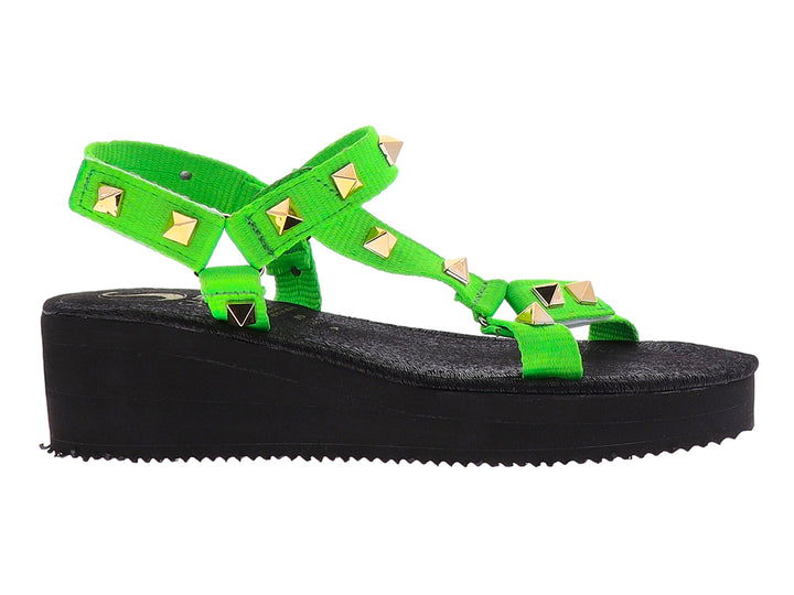 Sandalia de plataforma negra con tiras verde neón y tachuelas doradas.