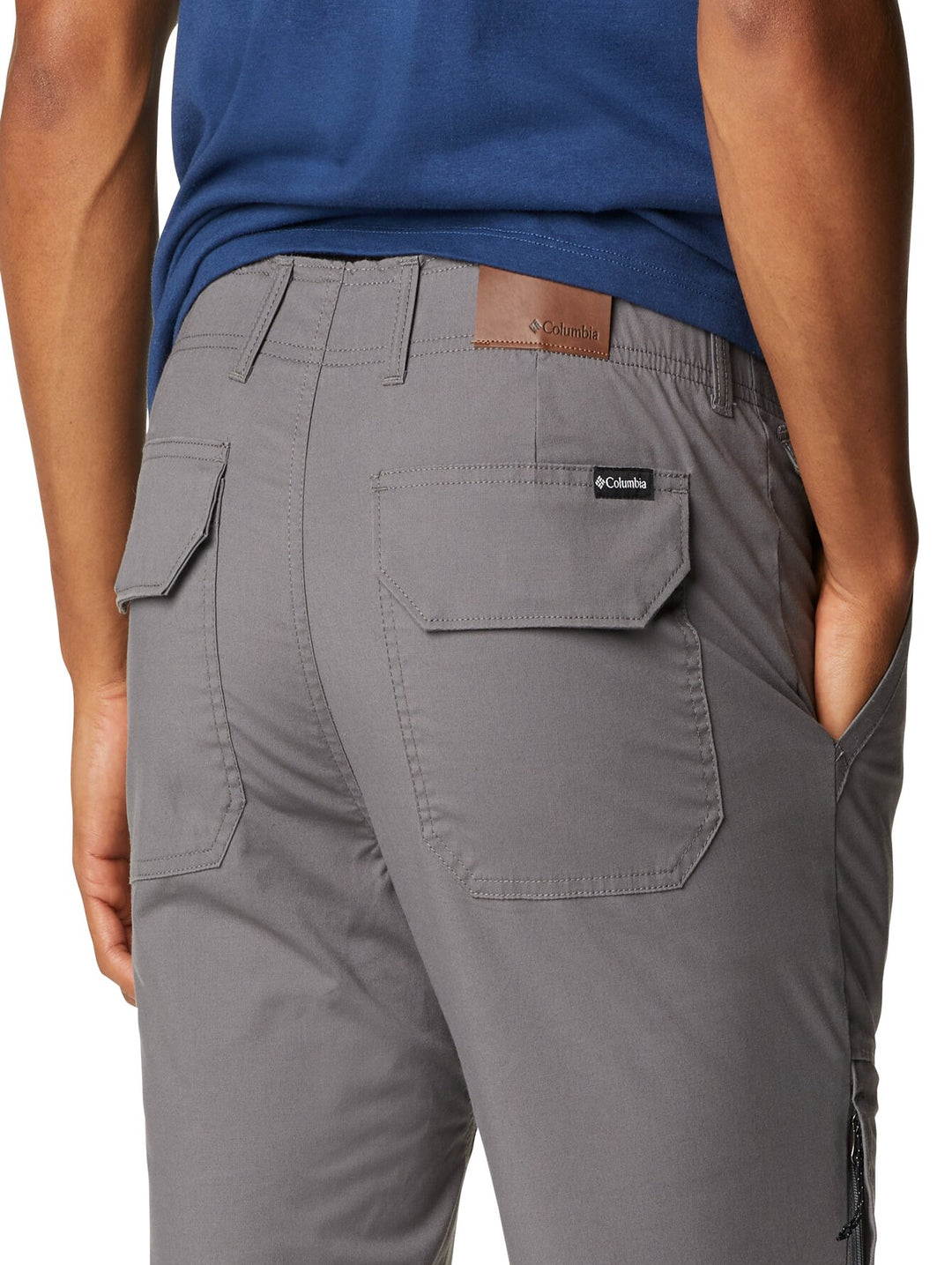 Hombre usando pantalones utilitarios color gris Columbia con bolsillos laterales.